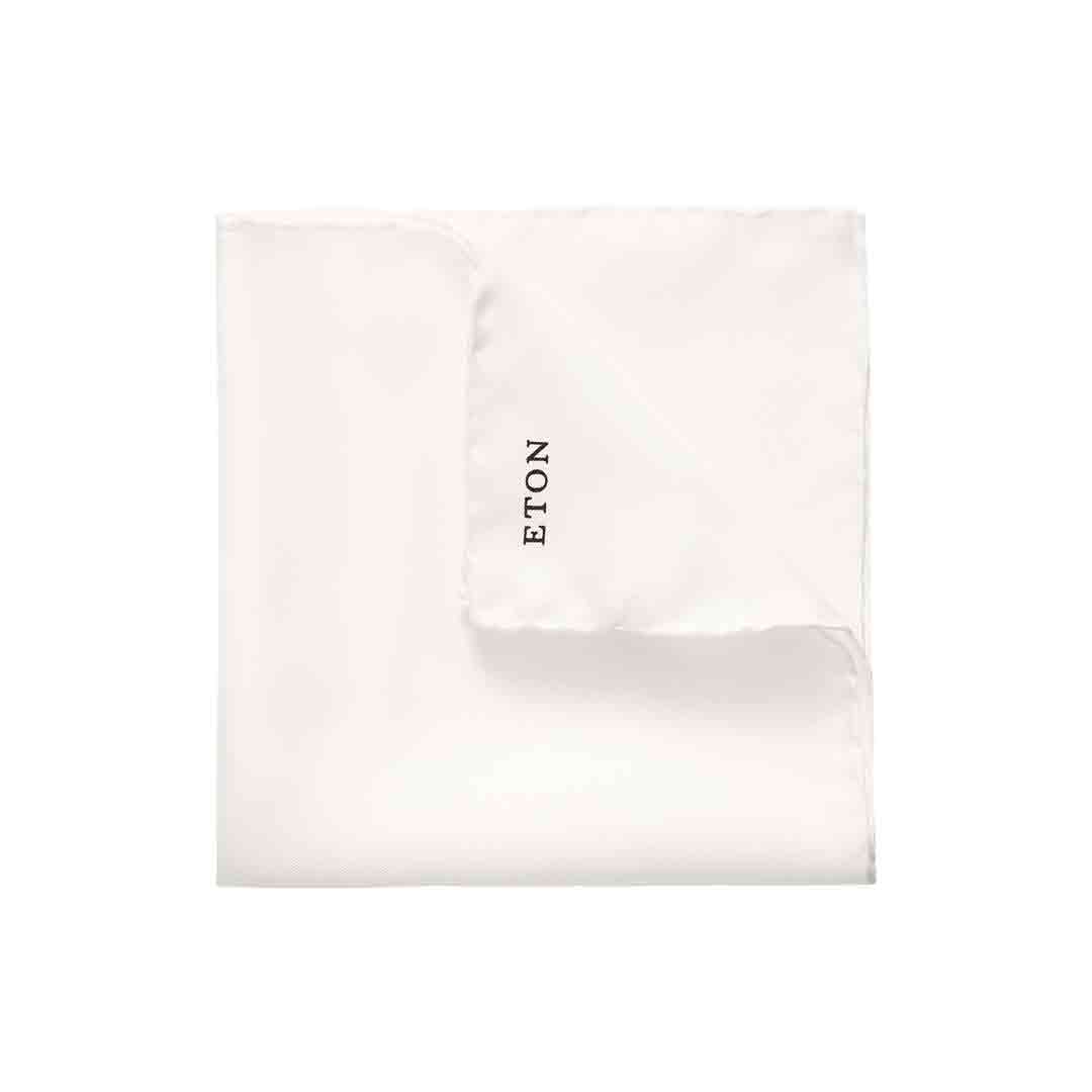 A folded white pocket square with the brand name 'ETON' printed in black on one corner, set against a plain white background. Eton Pocket Square available at Sakks Menswear in Southampton.