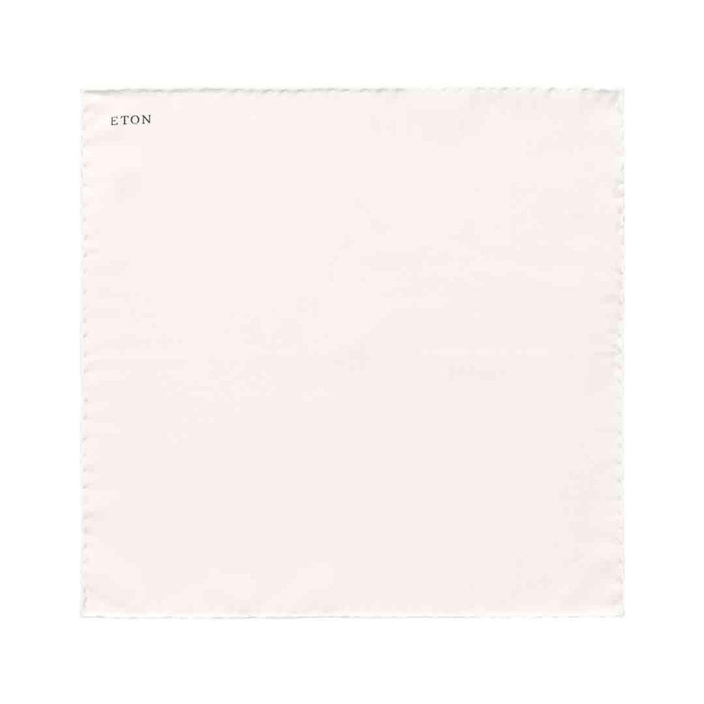 A square off-white cotton pocket square with a fine stitched border and the brand name 'ETON' printed in black in the top-left corner, shown on a solid white background. Eton Pocket Square available at Sakks Menswear in Southampton.