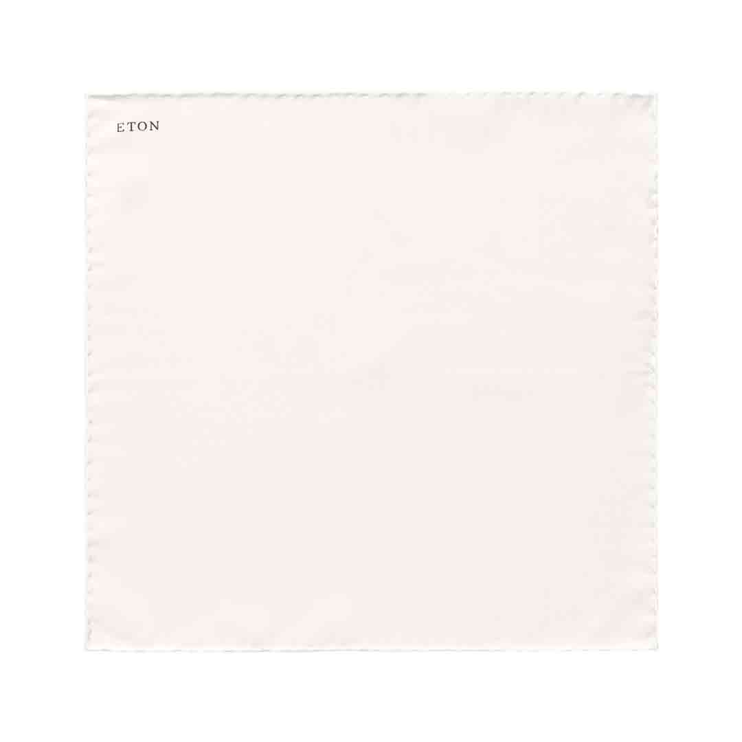 A square off-white cotton pocket square with a fine stitched border and the brand name 'ETON' printed in black in the top-left corner, shown on a solid white background. Eton Pocket Square available at Sakks Menswear in Southampton.