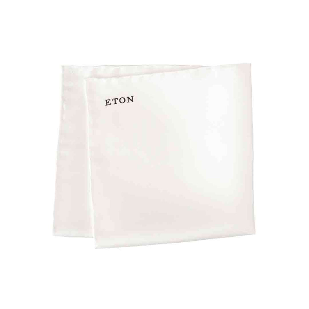 A white square fabric pocket square with the brand name 'ETON' printed in black serif text near the top left corner, shown on a plain white background. Eton Pocket Square available at Sakks Menswear in Southampton.