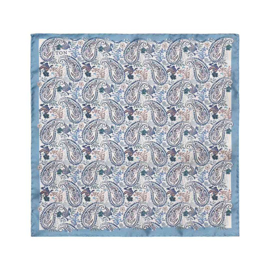 A square cotton pocket square with a classic paisley pattern in shades of blue, beige, and brown, finished with a solid light blue border. The brand name 'TON' is printed in the top-left corner. Eton Pocket Square available at Sakks Menswear in Southampton.