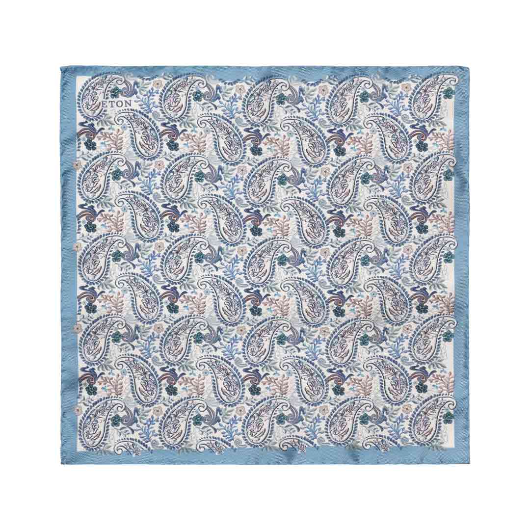 A square cotton pocket square with a classic paisley pattern in shades of blue, beige, and brown, finished with a solid light blue border. The brand name 'TON' is printed in the top-left corner. Eton Pocket Square available at Sakks Menswear in Southampton.