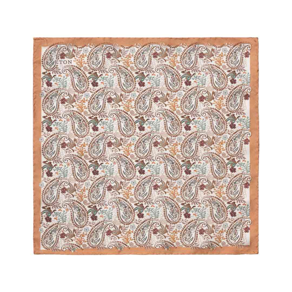 A square cotton pocket square by Eton, featuring a detailed paisley pattern in muted tones of brown, beige, light blue, and burgundy on a cream background, finished with a solid tan border.  Eton Pocket Square available at Sakks Menswear in Southampton.