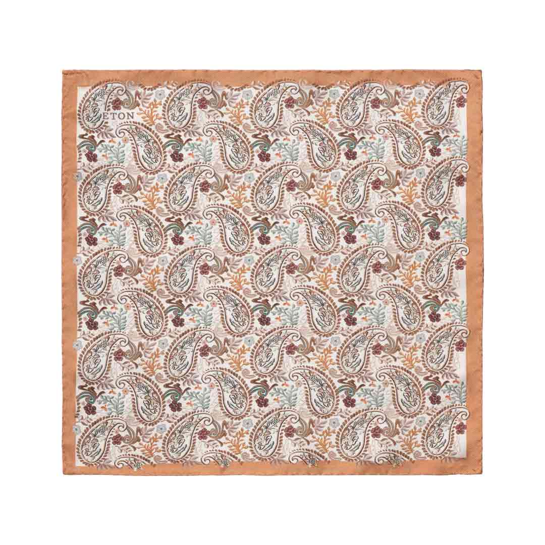 A square cotton pocket square by Eton, featuring a detailed paisley pattern in muted tones of brown, beige, light blue, and burgundy on a cream background, finished with a solid tan border.  Eton Pocket Square available at Sakks Menswear in Southampton.