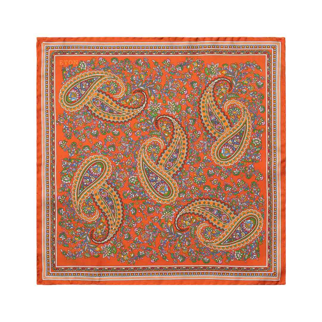 A square scarf with a vibrant orange background, featuring a detailed paisley pattern in gold, green, purple, and blue, finished with a decorative border. Eton Pocket Square available at Sakks Menswear in Southampton.