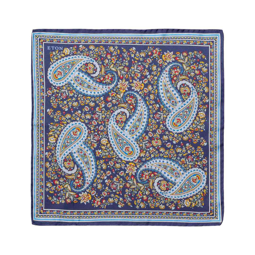 A square silk bandana featuring a classic paisley pattern in navy blue, light blue, white, and gold, with a dense floral background. The brand name 'ETON' is printed in the top-left corner. Eton Pocket Square available at Sakks Menswear in Southampton.