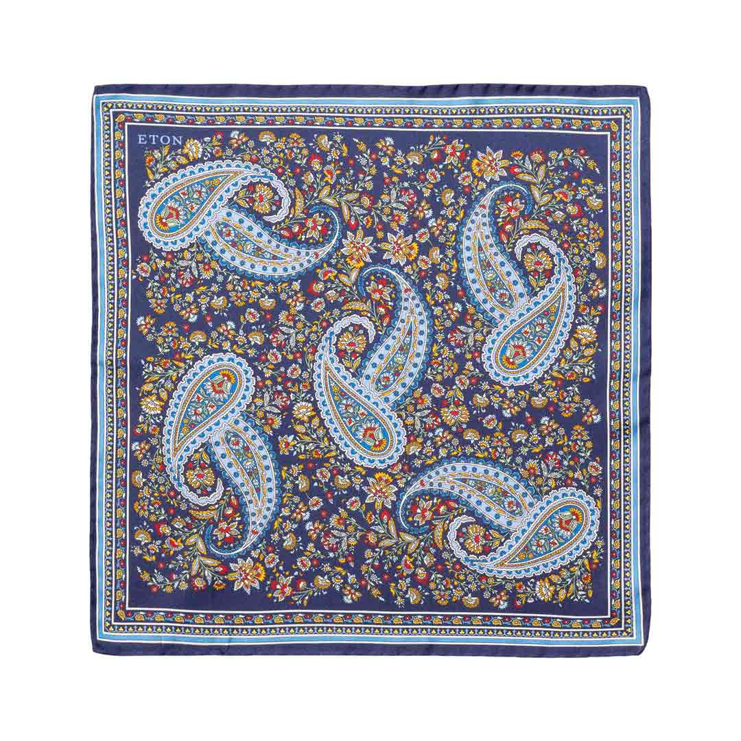 A square silk bandana featuring a classic paisley pattern in navy blue, light blue, white, and gold, with a dense floral background. The brand name 'ETON' is printed in the top-left corner. Eton Pocket Square available at Sakks Menswear in Southampton.