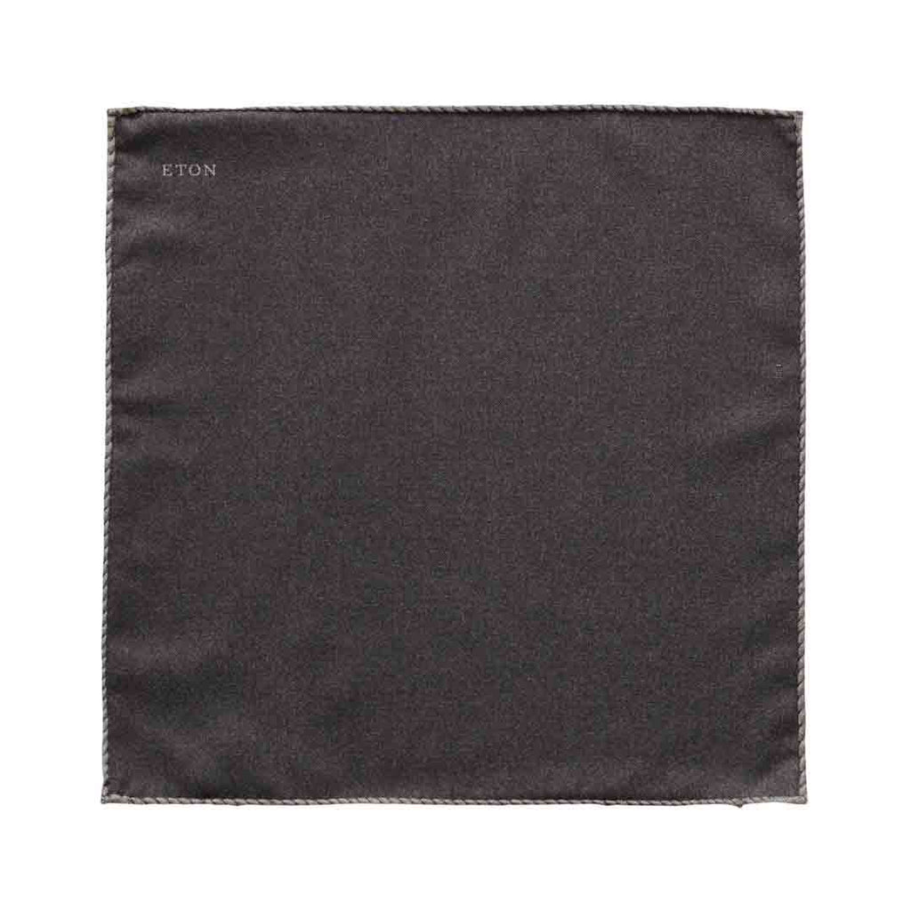 A square dark charcoal gray pocket square with a stitched border and the brand name 'ETON' printed in small white letters in the top-left corner, shown on a plain white background. Eton Pocket Square available at Sakks Menswear in Southampton.