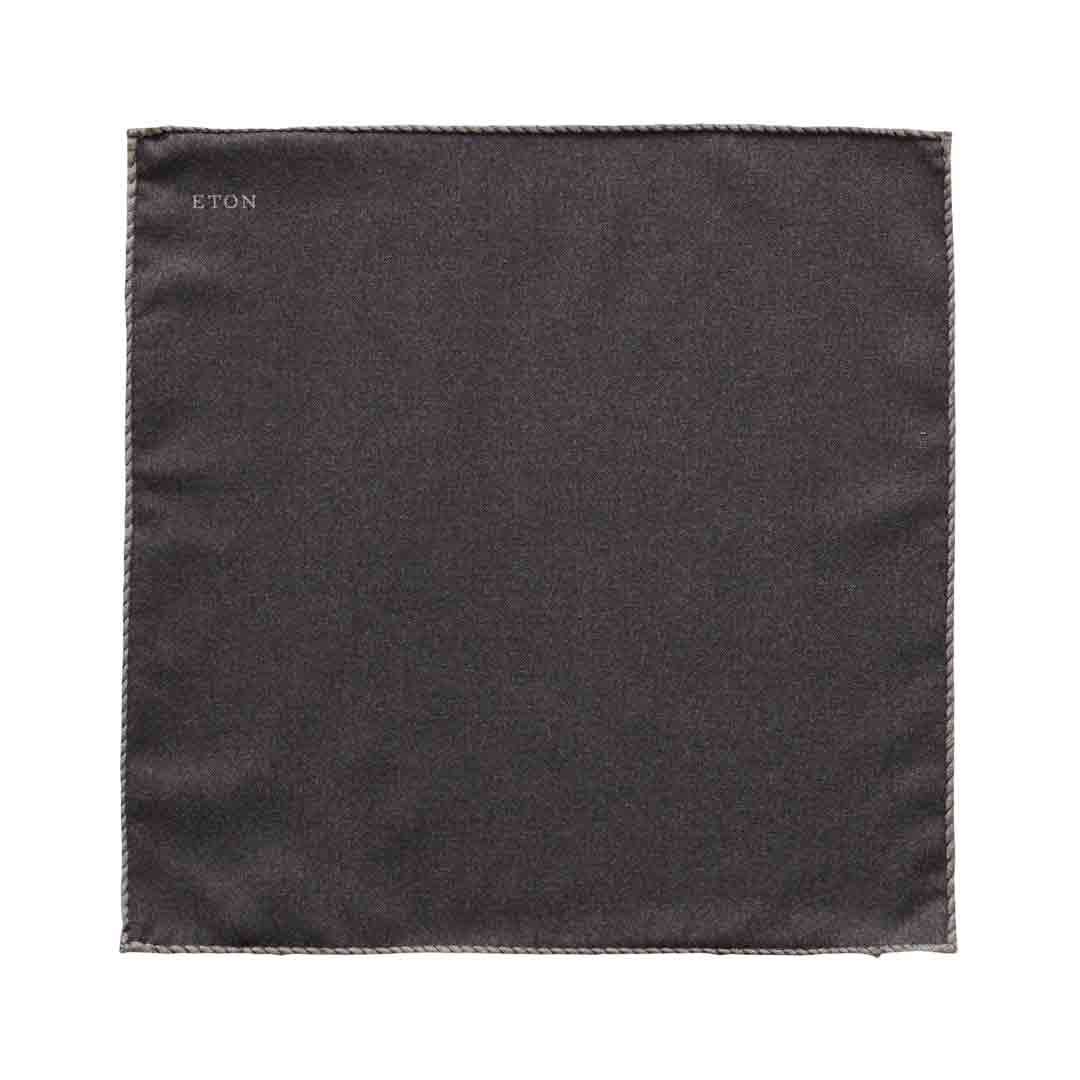 A square dark charcoal gray pocket square with a stitched border and the brand name 'ETON' printed in small white letters in the top-left corner, shown on a plain white background. Eton Pocket Square available at Sakks Menswear in Southampton.