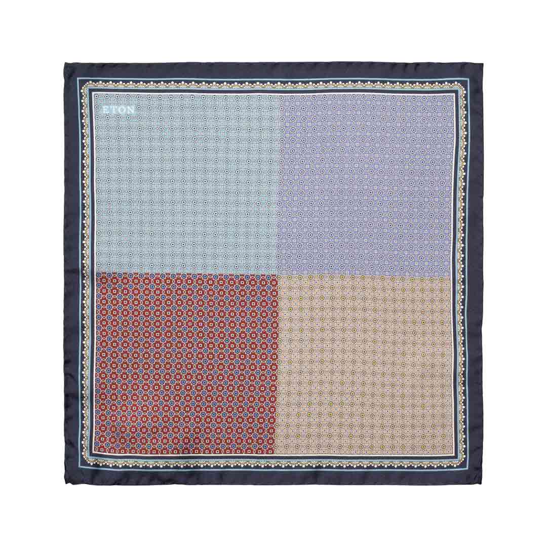 A square pocket square with a four-quadrant patterned design in light blue, lavender, rust red, and beige, framed by a dark navy border with a decorative geometric pattern. Eton Pocket Square available at Sakks Menswear in Southampton.
