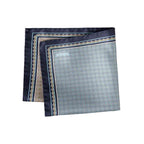A folded square silk pocket square with a light blue and gray geometric pattern, dark navy borders, and gold accents, featuring the brand name 'ETON' printed in the top left corner. Eton Pocket Square available at Sakks Menswear in Southampton.