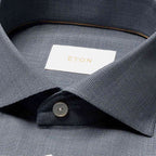 Close-up of a textured ETON dress shirt collar with a white neck label featuring gold lettering and a single button. Eton Shirt available at Sakks Menswear in Southampton.
