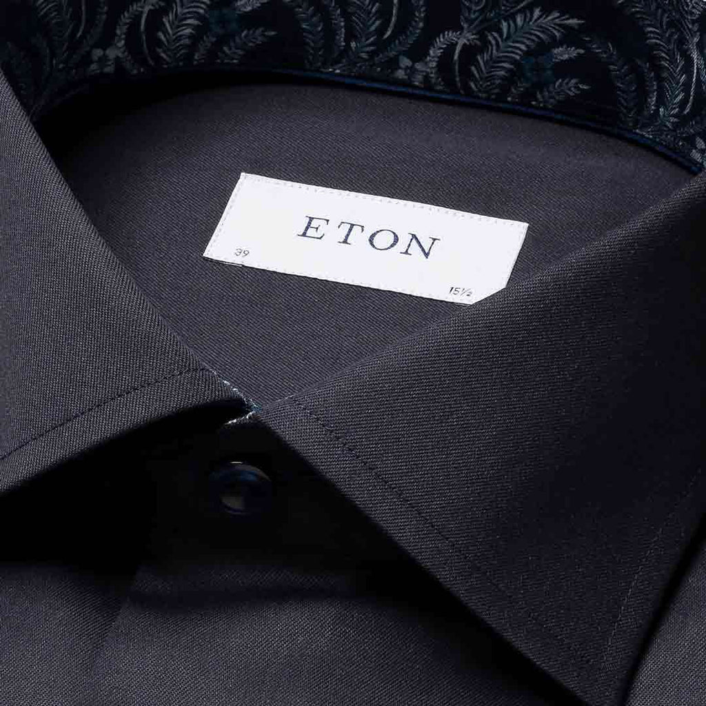Close-up of a dark charcoal gray dress shirt collar with a white neck label reading ETON, showing part of a patterned inner collar lining. Eton Shirt available at Sakks Menswear in Southampton.