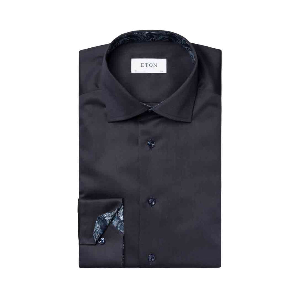 A folded black dress shirt with a patterned inner collar and cuff, featuring a white neck label that reads 'ETON', set against a plain white background. Eton Shirt available at Sakks Menswear in Southampton.