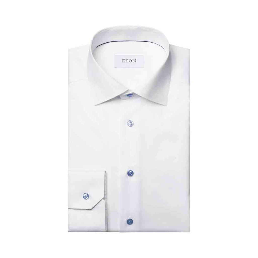 A folded white dress shirt with a pointed collar, button-down front, and a single cuff, shown on a plain white background. The brand name 'ETON' is visible on the inner neck label. Eton Shirt available at Sakks Menswear in Southampton.