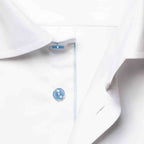 Close-up of a white dress shirt collar with a single light blue button and a thin light blue stripe detail along the placket. Eton Shirt available at Sakks Menswear in Southampton.