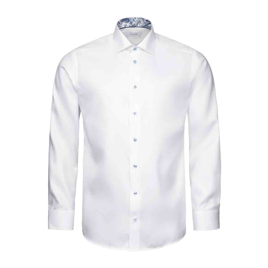 A white long-sleeve dress shirt with a pointed collar, button-down front, and a blue paisley patterned inner collar, shown on a plain white background. Eton Shirt available at Sakks Menswear in Southampton.
