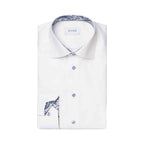 A folded white dress shirt with a blue paisley patterned inner collar and matching pocket square, featuring light blue buttons and the brand name ETON on the collar label. Eton Shirt available at Sakks Menswear in Southampton.