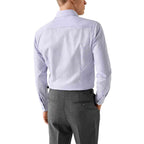 A man shown from the back wearing a light lavender long-sleeve dress shirt tucked into dark gray trousers, against a plain white background. Eton Shirt available at Sakks Menswear in Southampton.