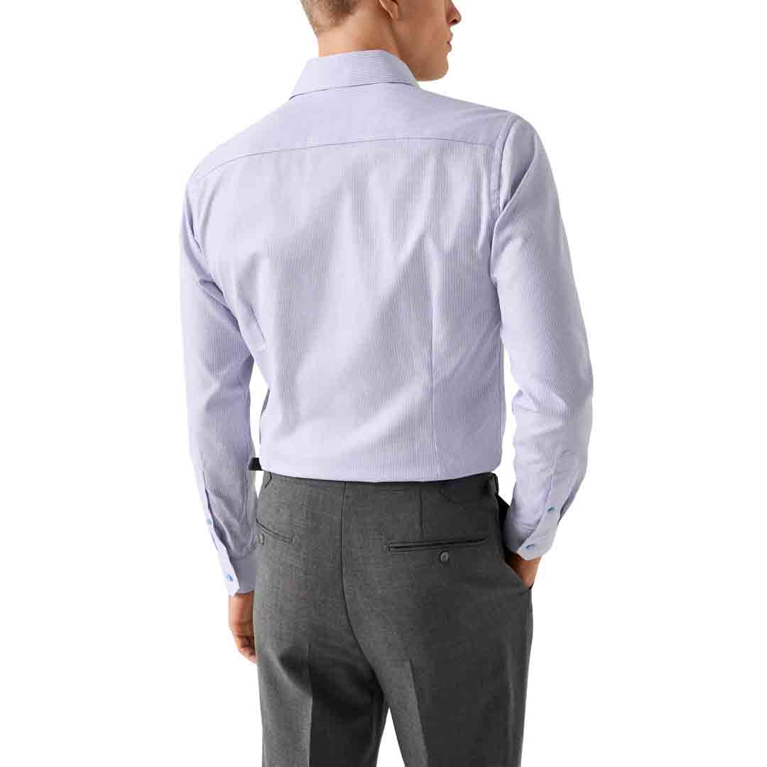 A man shown from the back wearing a light lavender long-sleeve dress shirt tucked into dark gray trousers, against a plain white background. Eton Shirt available at Sakks Menswear in Southampton.