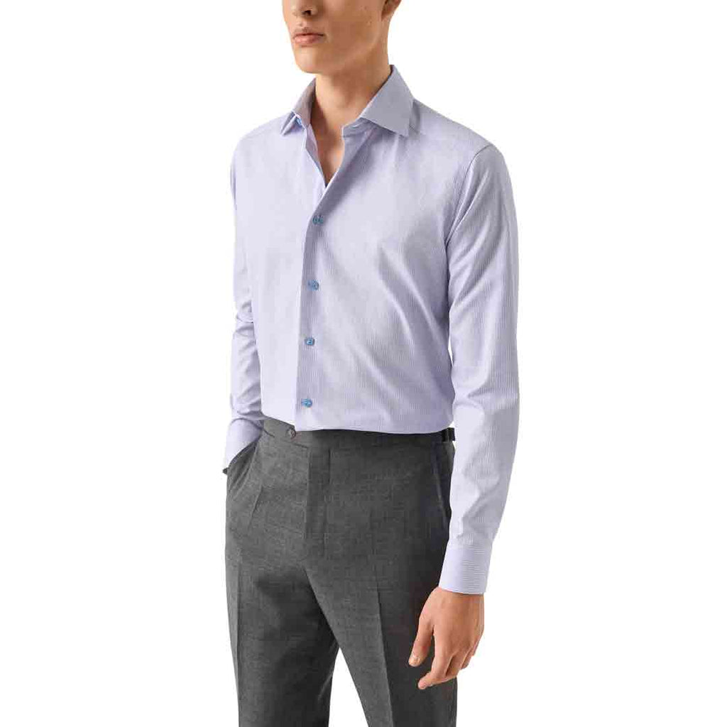 A man wearing a light lavender long-sleeve button-down dress shirt tucked into dark gray trousers, shown from the chin down against a plain white background. Eton Shirt available at Sakks Menswear in Southampton.