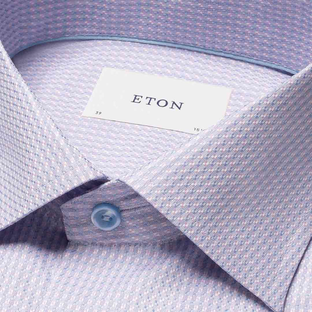 Close-up of a light lavender and white micro-patterned dress shirt collar with a visible ETON brand label and a light blue button. Eton Shirt available at Sakks Menswear in Southampton.