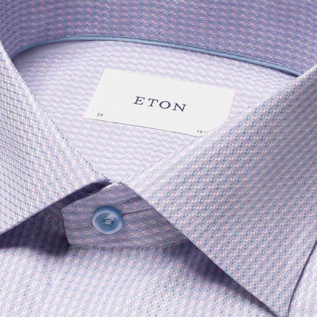 Close-up of a light lavender and white micro-patterned dress shirt collar with a visible ETON brand label and a light blue button. Eton Shirt available at Sakks Menswear in Southampton.