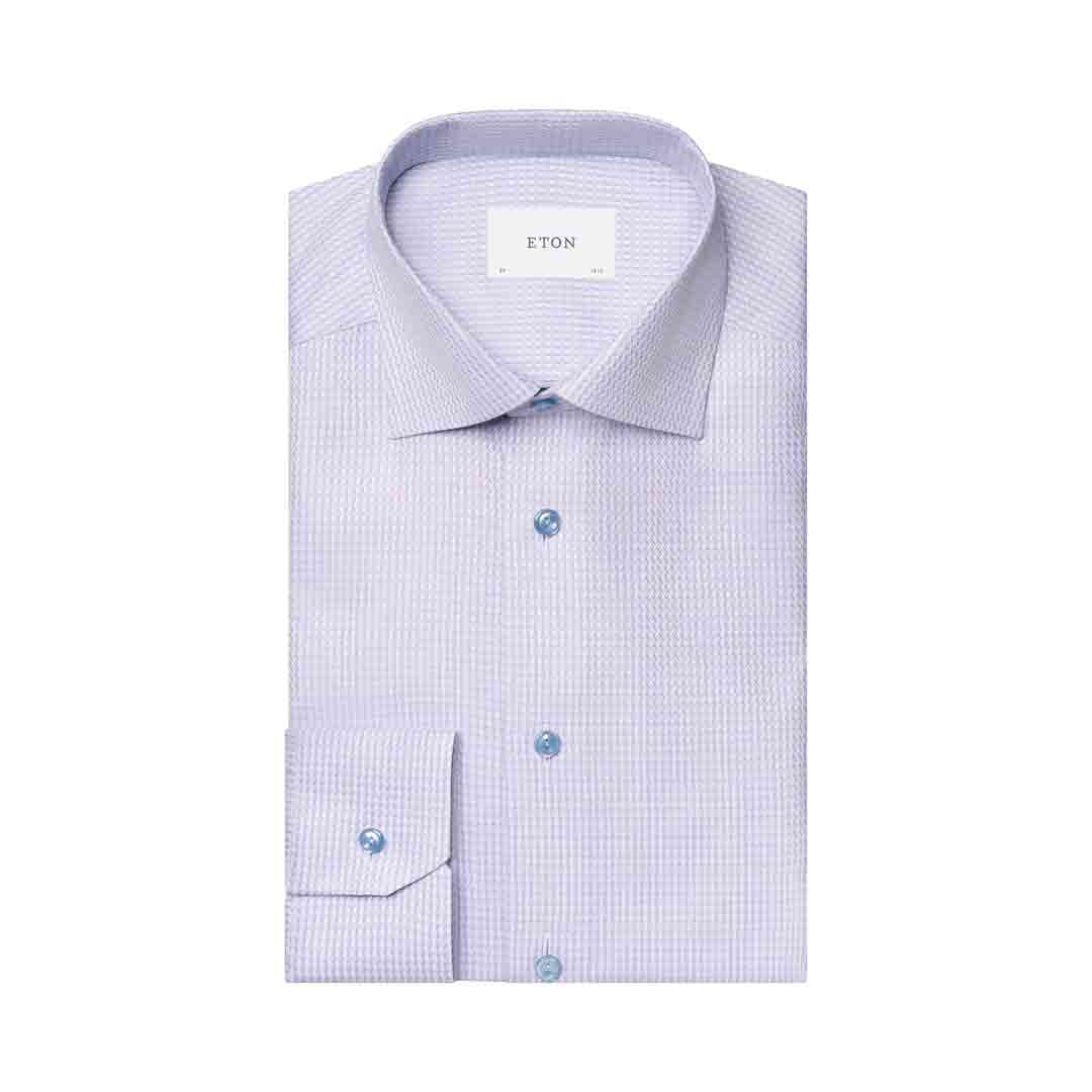 A folded light purple and white micro-check patterned dress shirt with a pointed collar, button-down front, and a visible ETON brand label inside the collar. Eton Shirt available at Sakks Menswear in Southampton.