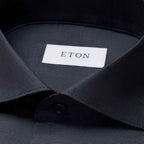 Close-up of a dark navy textured dress shirt collar with a white neck label reading ETON. Eton Shirt available at Sakks Menswear in Southampton.