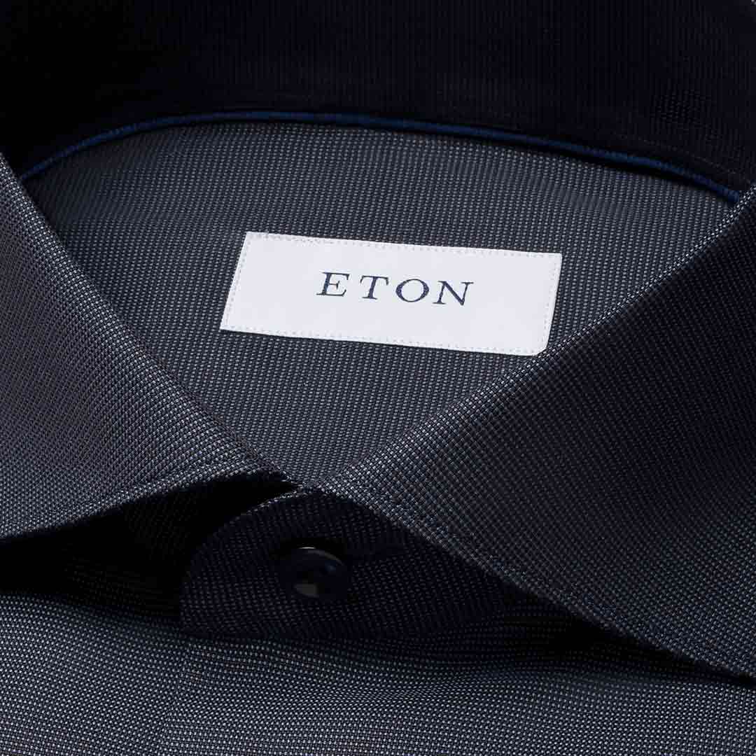 Close-up of a dark navy textured dress shirt collar with a white neck label reading ETON. Eton Shirt available at Sakks Menswear in Southampton.
