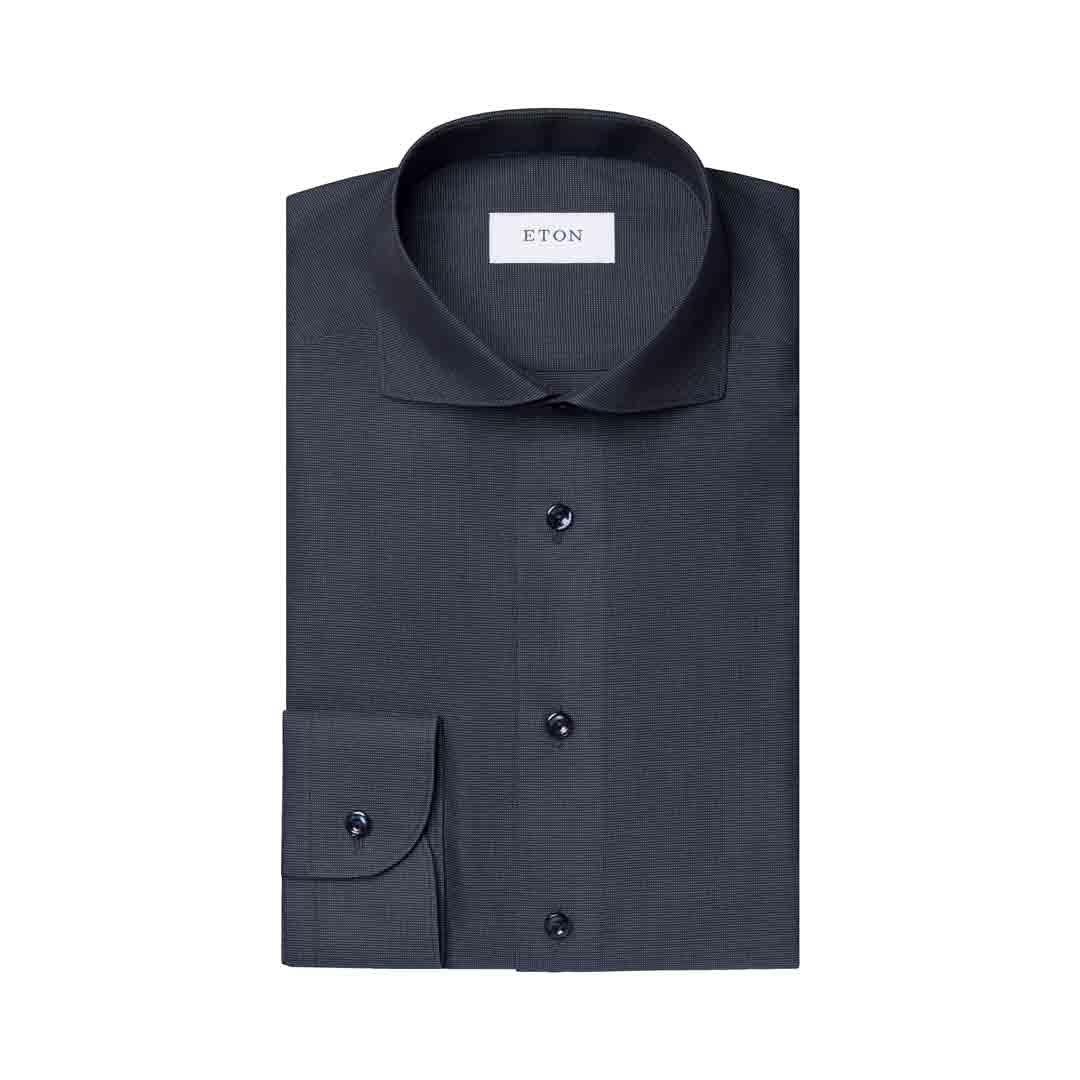 A dark charcoal gray ETON dress shirt folded neatly, showing a classic collar, button-down front, and a single cuff with a button, set against a plain white background. Eton Shirt available at Sakks Menswear in Southampton.