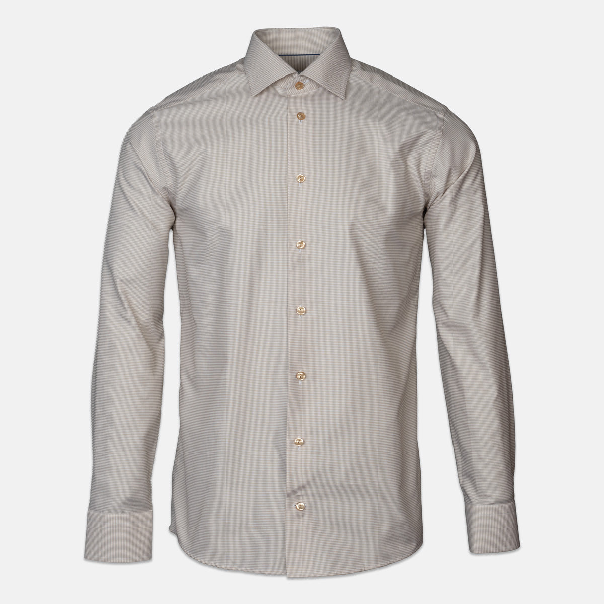 A light beige shirt with brown buttons in front of a light grey background. Eton shirts available at Sakks Menswear in Southampton.