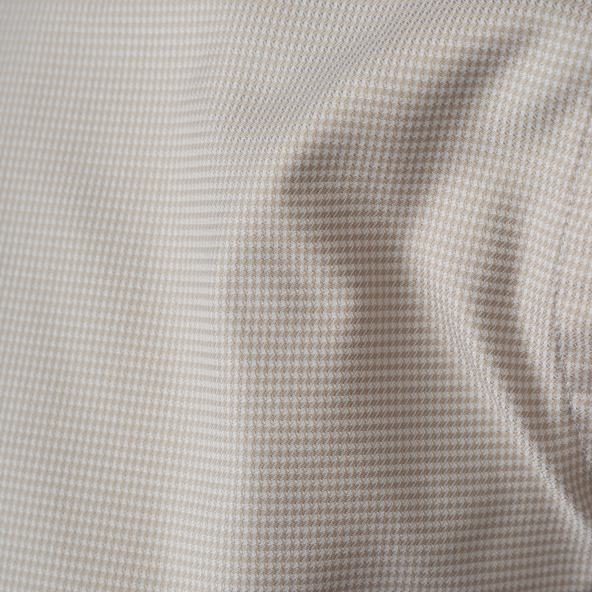 Close-up of a fine micro-check fabric pattern in beige and white, showing soft folds and texture.  Eton shirts available at Sakks Menswear in Southampton.