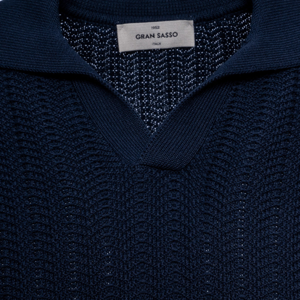Close-up of a dark navy blue knit sweater with a textured pattern and a white brand label reading 'GRAN SASSO' at the collar. Gran Sasso Polo available at Sakks Menswear in Southampton.