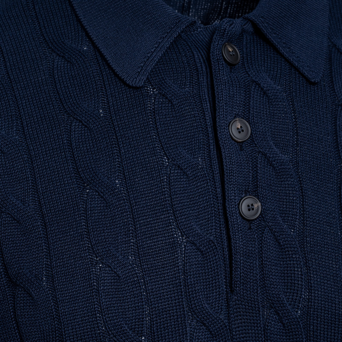 Close-up of a dark navy blue cable-knit polo shirt showing the collar, three buttons, and detailed knit texture. Gran Sasso Polo available at Sakks Menswear in Southampton.
