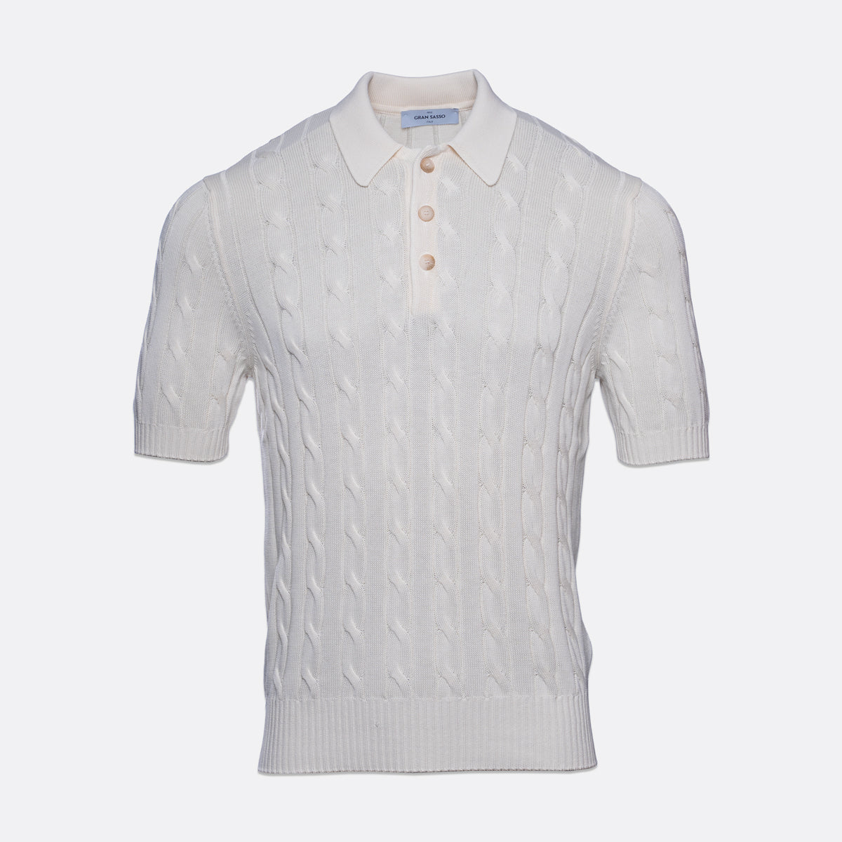 A white short-sleeve knit polo shirt with a cable pattern, featuring a three-button placket and a classic collar, shown against a light grey background. Gran Sasso Polo available at Sakks Menswear in Southampton.