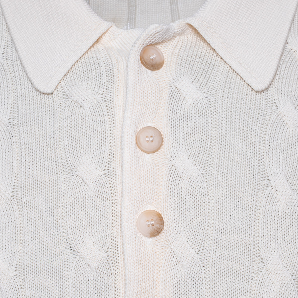Close-up of a cream-coloured cable-knit polo shirt with a pointed collar and three matching buttons. Gran Sasso Polo available at Sakks Menswear in Southampton.