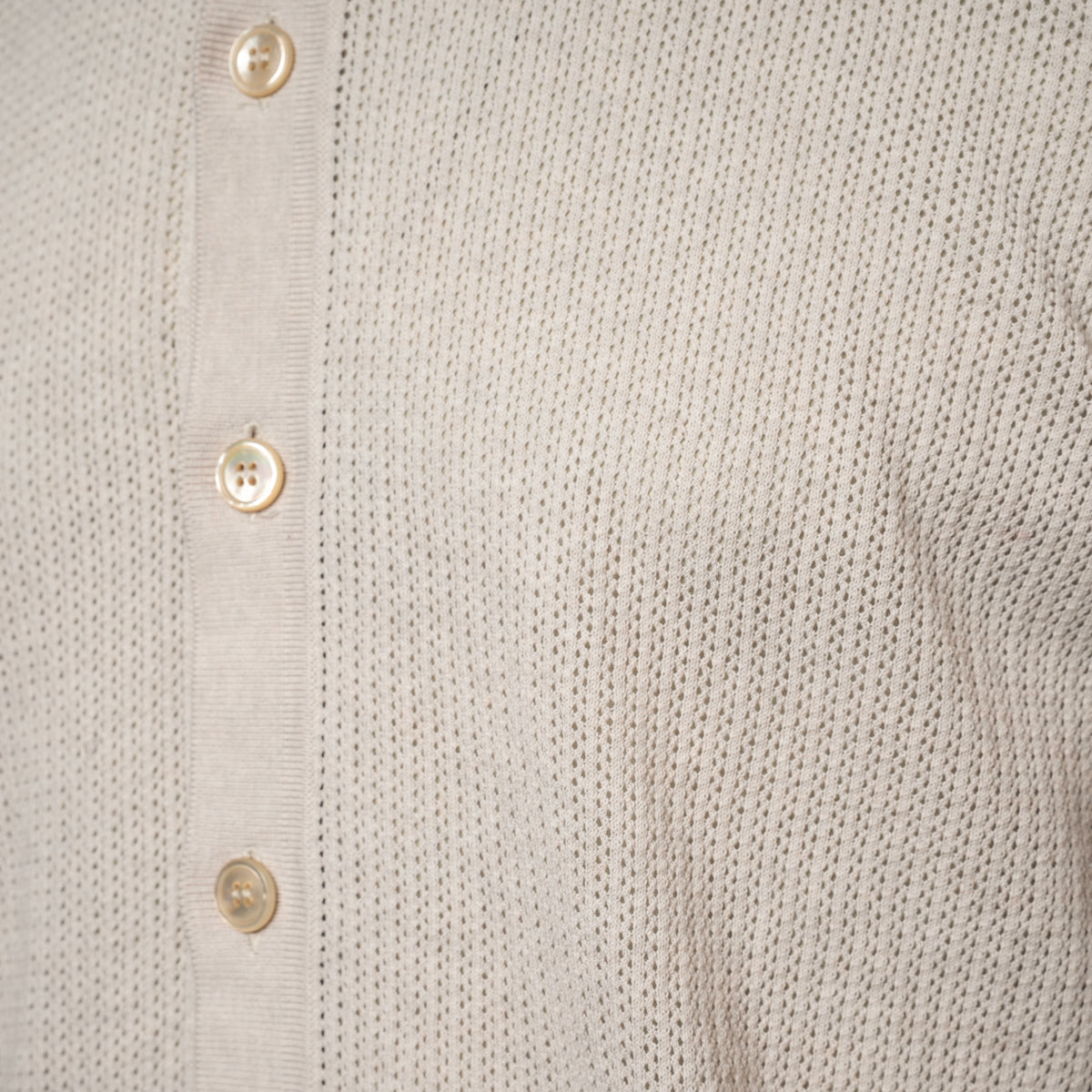 Close-up of a light beige knit shirt with a vertical button placket and cream-colored buttons. Gran Sasso Polo available at Sakks Menswear in Southampton.
