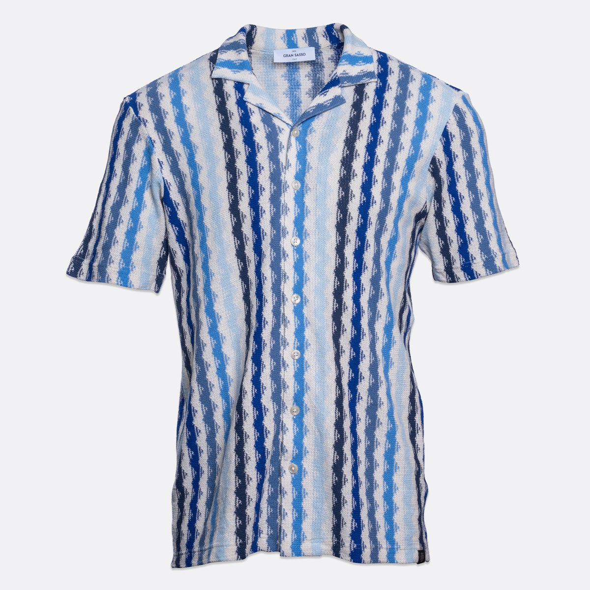 A short-sleeve button-up shirt with a vertical wavy stripe pattern in shades of blue, navy, and white, shown against a light grey background. Gran Sasso Short Sleeve Shirt available at Sakks Menswear in Southampton.