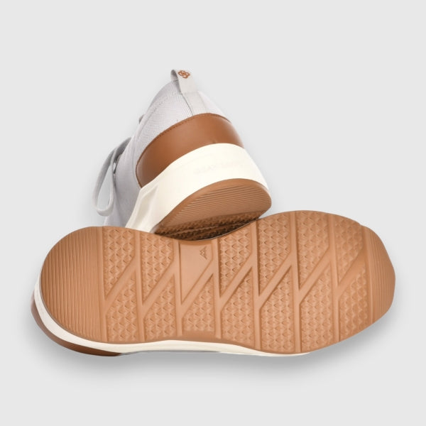 Close-up of a shoe with a brown sole on a light grey background. Gran Sasso Sneakers available at Sakks Menswear in Southampton.
