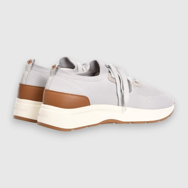 A pair of light grey knit slip-on sneakers with brown leather heel accents, white midsoles, and gum outsoles, shown from a side profile view on a light grey background. Gran Sasso Sneakers available at Sakks Menswear in Southampton.