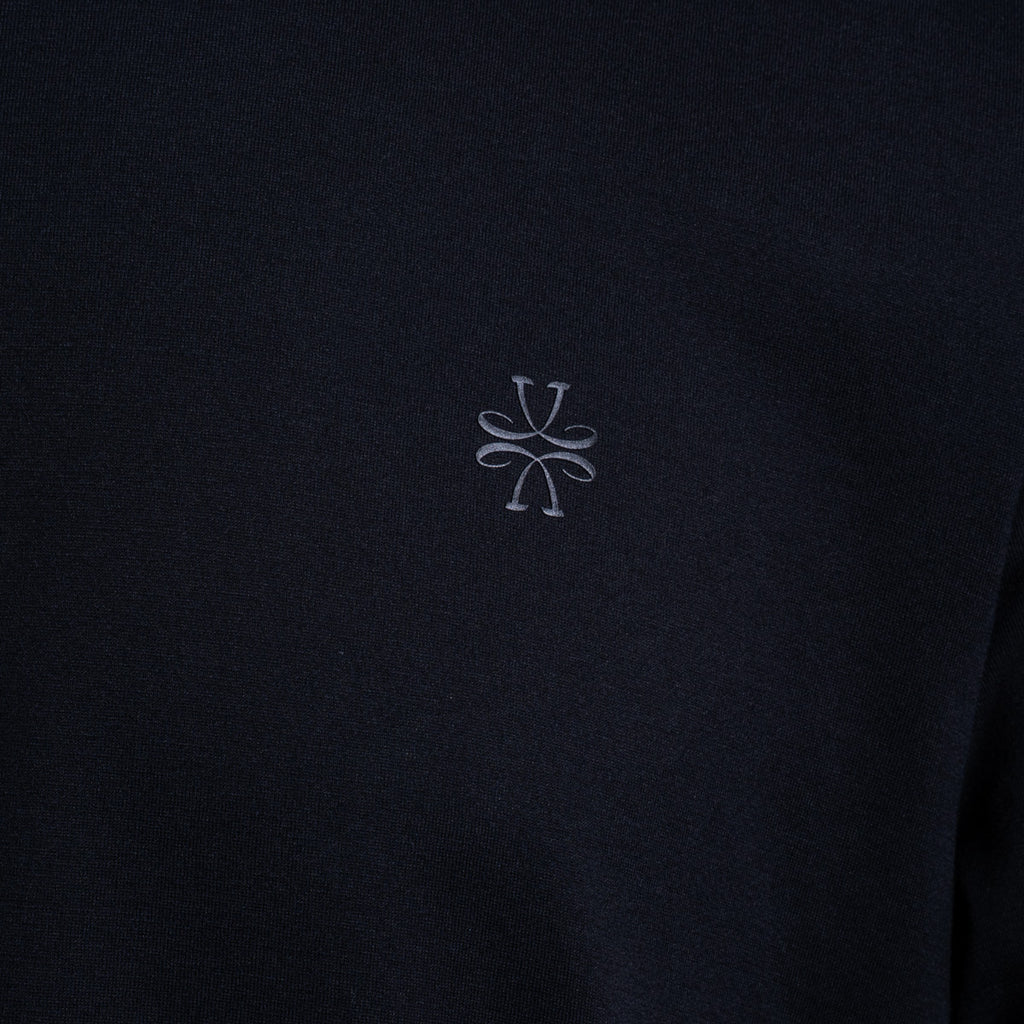 Close-up of a dark navy fabric with a small light gray embroidered logo in the center. Jacob Cohën T-Shirt available at Sakks Menswear in Southampton.