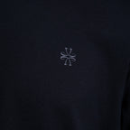 Close-up of a dark navy fabric with a small light gray embroidered logo in the center. Jacob Cohën T-Shirt available at Sakks Menswear in Southampton.