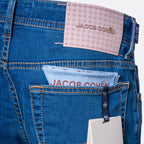 Close-up of the back waistband and pocket area of blue denim jeans with a pink Jacob Cohen label at the back waist and a light blue paper insert in the back pocket. Jacob Cohën Jeans available at Sakks Menswear in Southampton.
