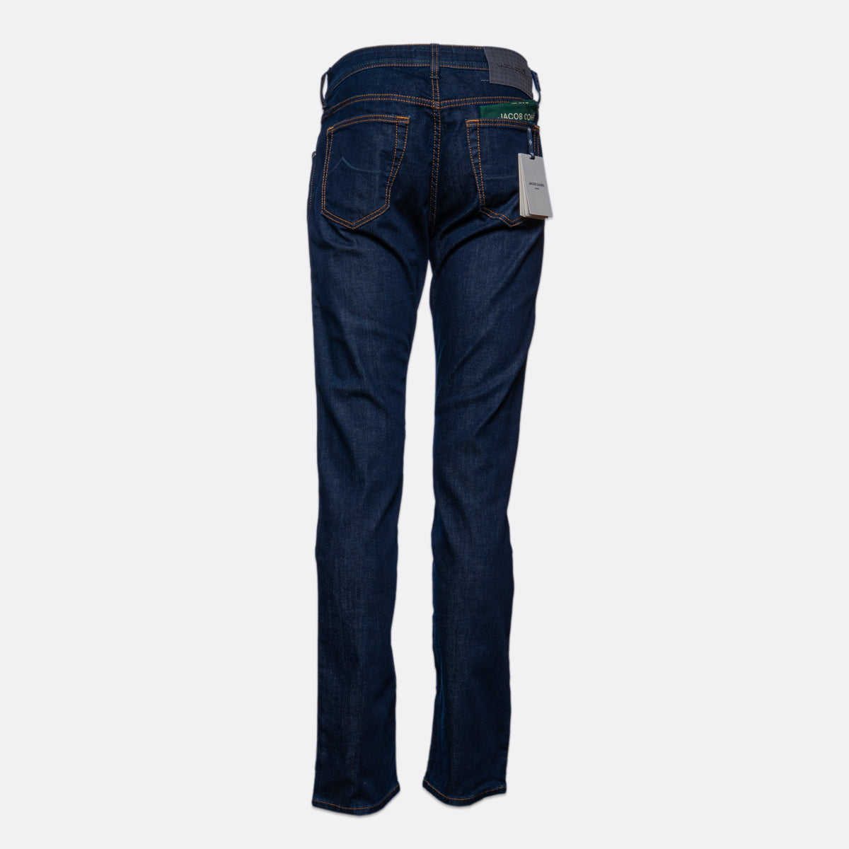 Back view of dark blue denim jeans with a gray waistband and a white hangtag, shown against a light gray background. Jacob Cohën Jeans available at Sakks Menswear in Southampton.