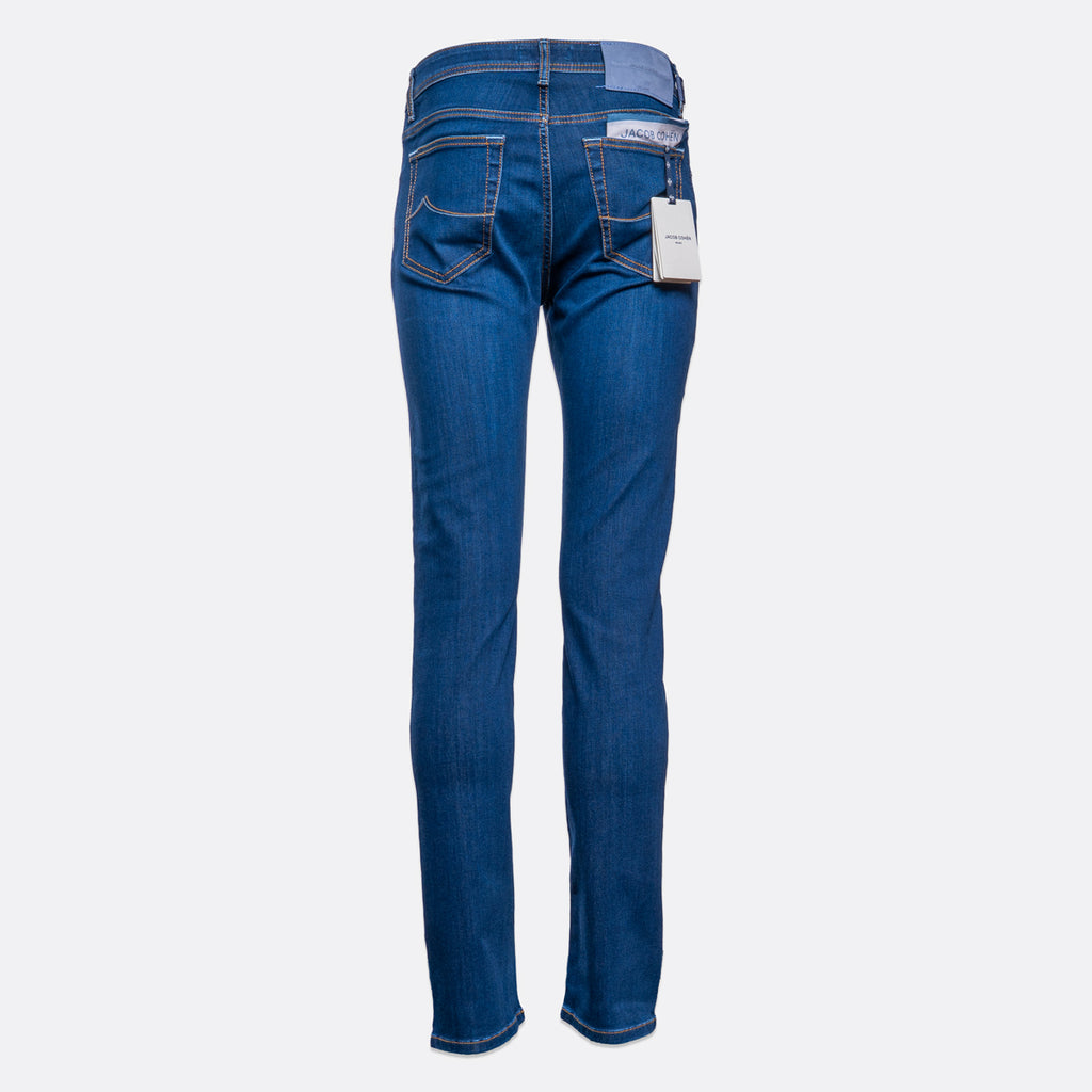 Back view of a pair of medium wash blue jeans with a white brand tag hanging from the back pocket, shown on a light gray background. Jacob Cohën Jeans available at Sakks Menswear in Southampton.