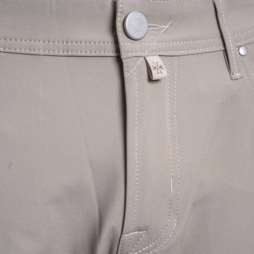 Close-up of the waistband of khaki trousers, showing a silver metal button, white contrast stitching, and a small beige fabric brand tag with a stylized logo. Jacob Cohën Chinos at Sakks Menswear in Southampton.
