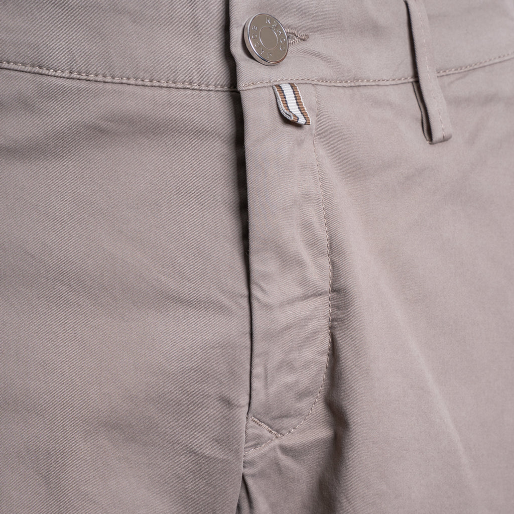 Close-up of a pair of light taupe-gray chino pants showing the waistband, button closure, belt loops, and front pocket stitching. Jacob Cohën Shorts available at Sakks Menswear in Southampton.