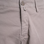 Close-up of a pair of light taupe-gray chino pants showing the waistband, button closure, belt loops, and front pocket stitching. Jacob Cohën Shorts available at Sakks Menswear in Southampton.