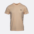 A light beige crewneck t-shirt with a small black geometric diamond logo on the left chest, displayed on a clean light gray background. MA.Strum T-Shirt available at Sakks Menswear in Southampton.